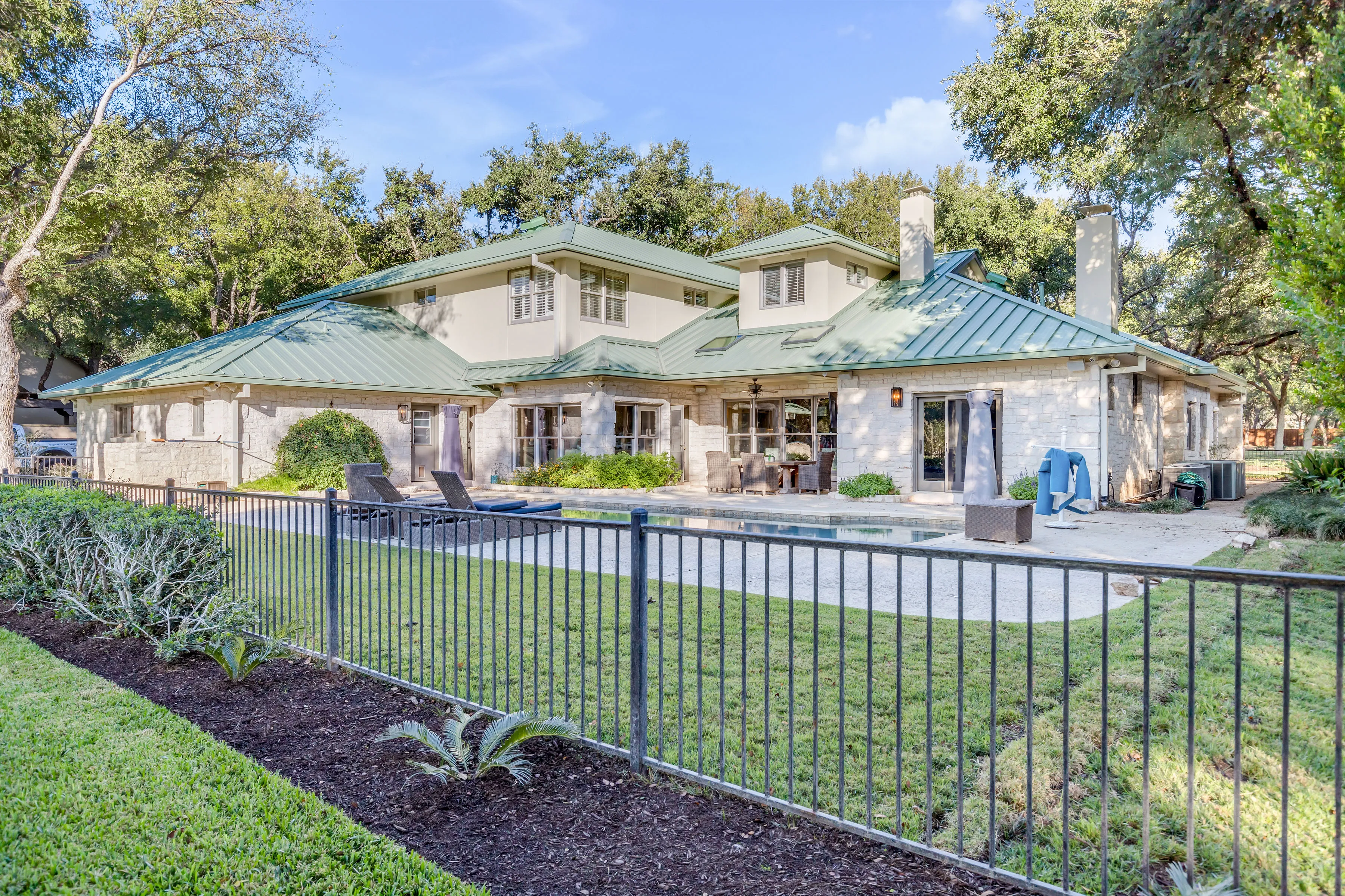 A stone home with a standing-seam metal roof completed by Ark Roofer