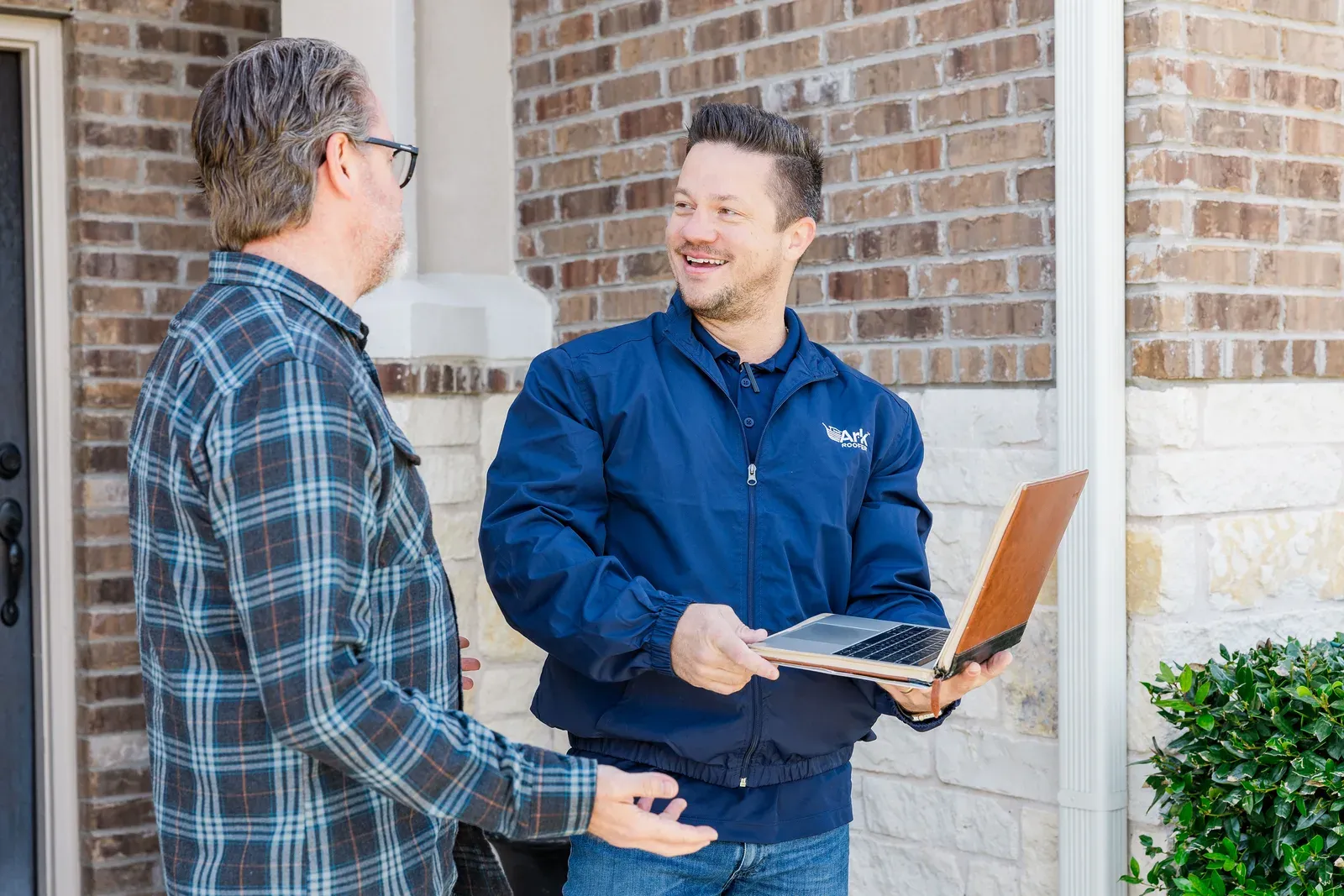 An Ark Roofer consultant reviewing inspection findings with a homeowner at the front door