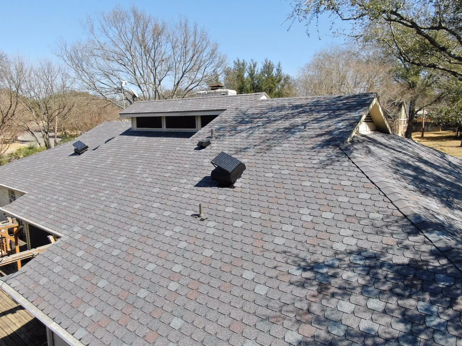 Gray shingle roof with solar attic fans