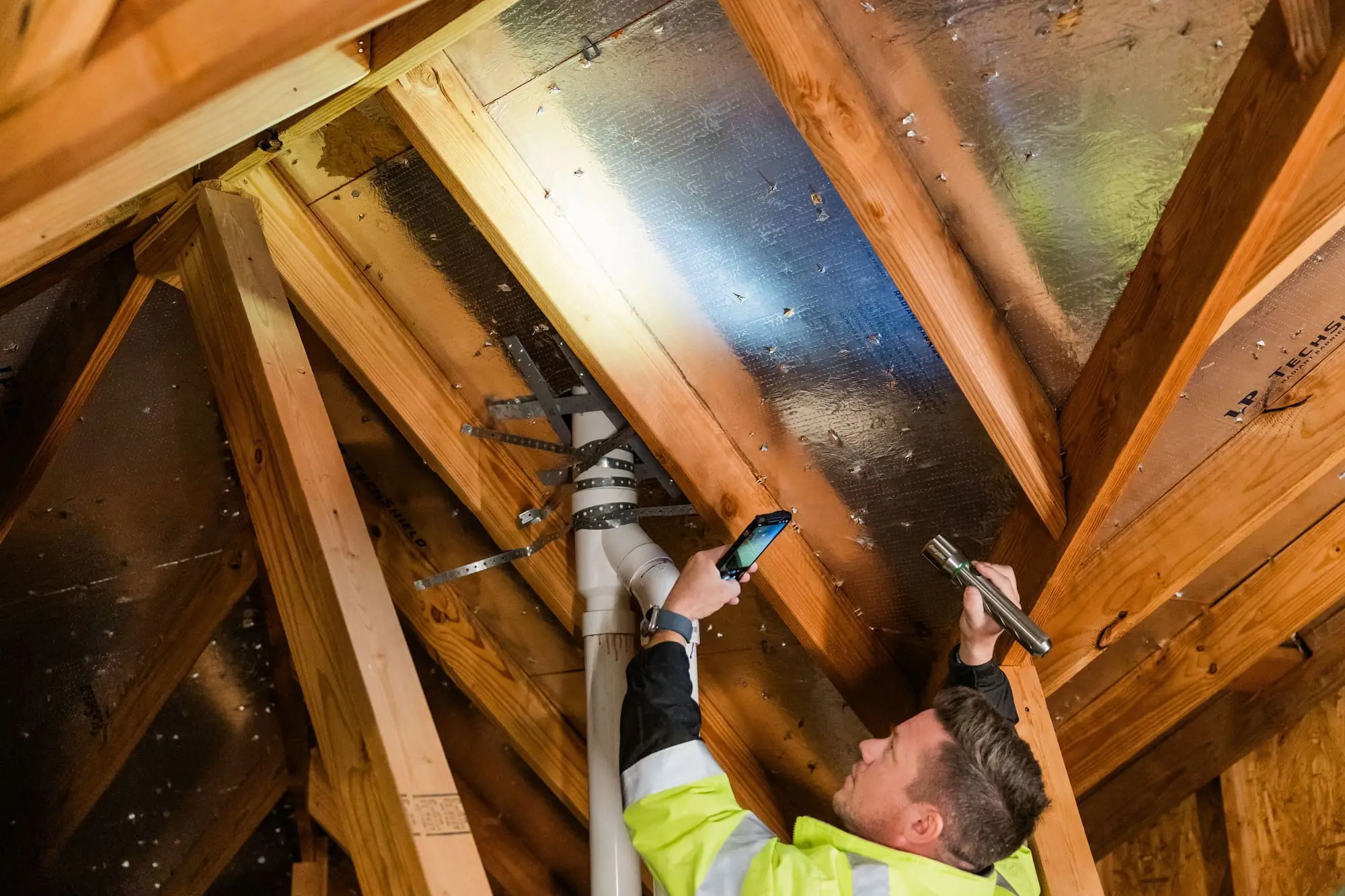 Ark inspector examining attic decking with a flashlight