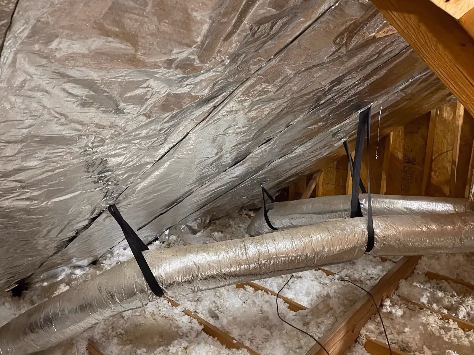 Reflective radiant barrier installed above attic insulation and ductwork