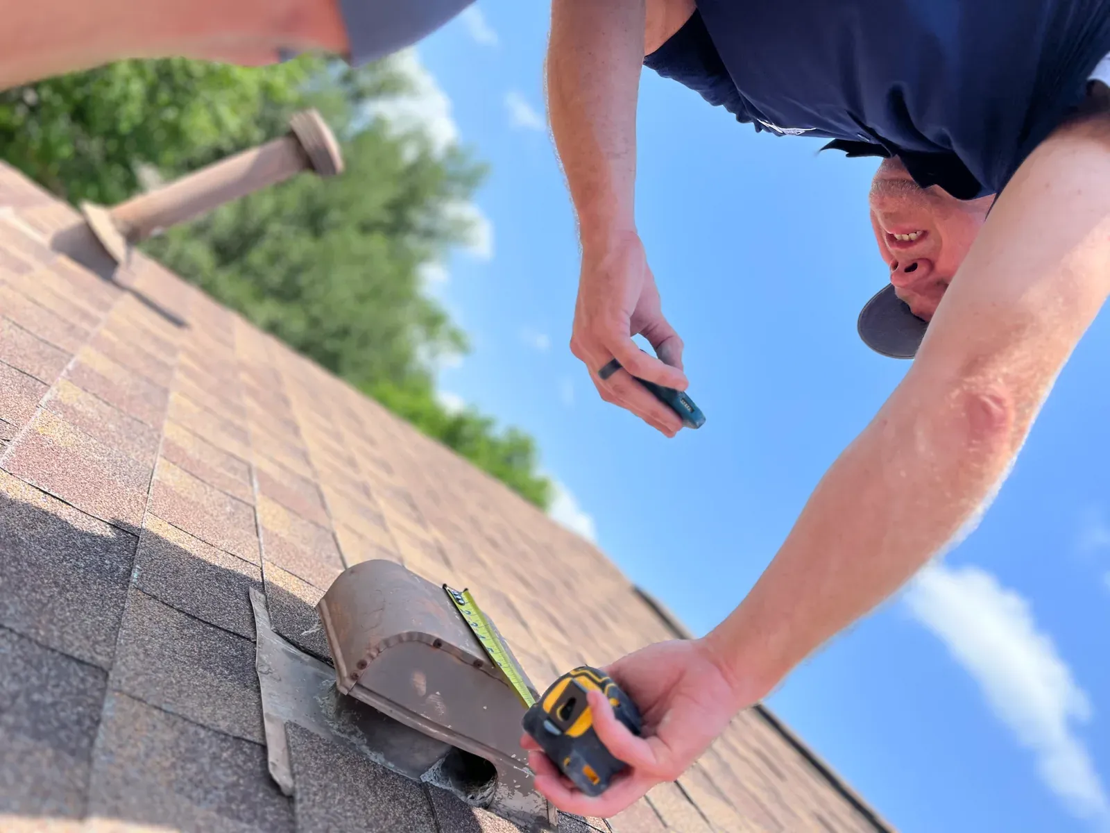 An Ark Roofer inspector measuring a damaged roof vent while documenting a storm claim