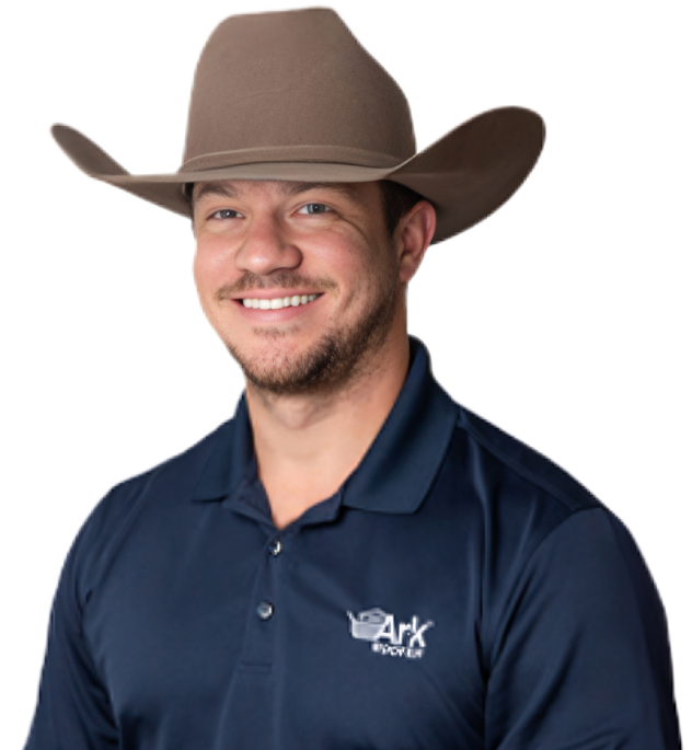 A smiling Ark Roofer professional wearing a cowboy hat and company-branded navy polo shirt.