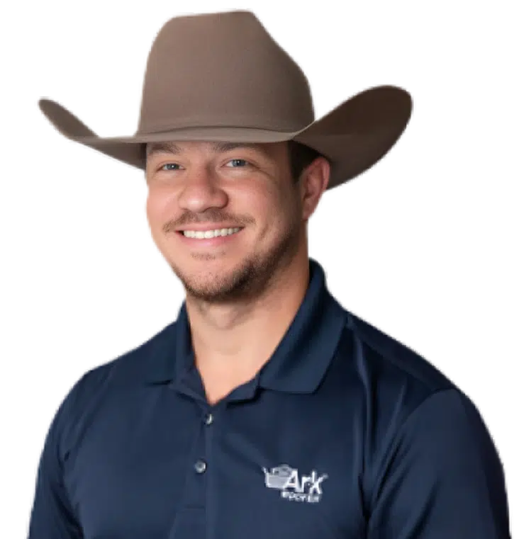 A smiling Ark Roofer professional wearing a cowboy hat and company-branded navy polo shirt.