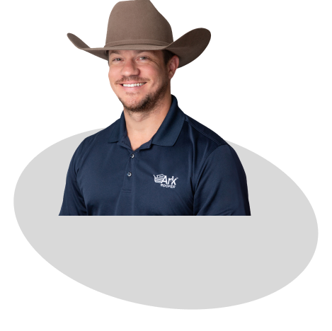 A smiling Ark Roofer professional wearing a cowboy hat and company-branded navy polo shirt.