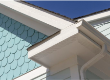 Detailed close-up of a corner of a roof with white gutters and fascia.