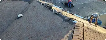 Roofing team working on the installation of shingles on a residential roof.