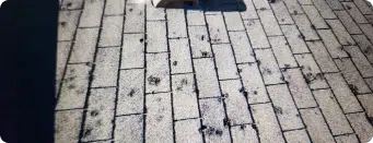 Roofing tiles with signs of wear and tear, showing damaged and weathered shingles.