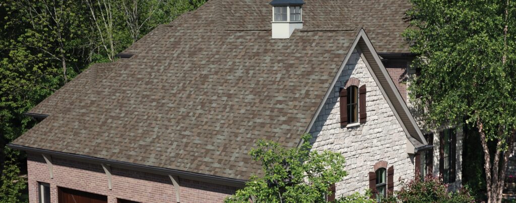 Asphalt shingle roof on a stone-clad house.