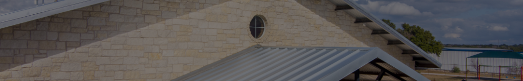 A metal roof installed on a building with a stone exterior wall and a circular window.