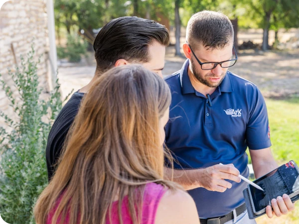 Ark Roofer team member explaining details to a couple using a tablet