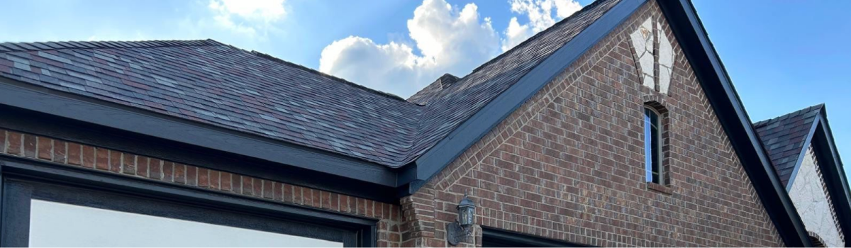 Brick house with a black roof and a dormer window.