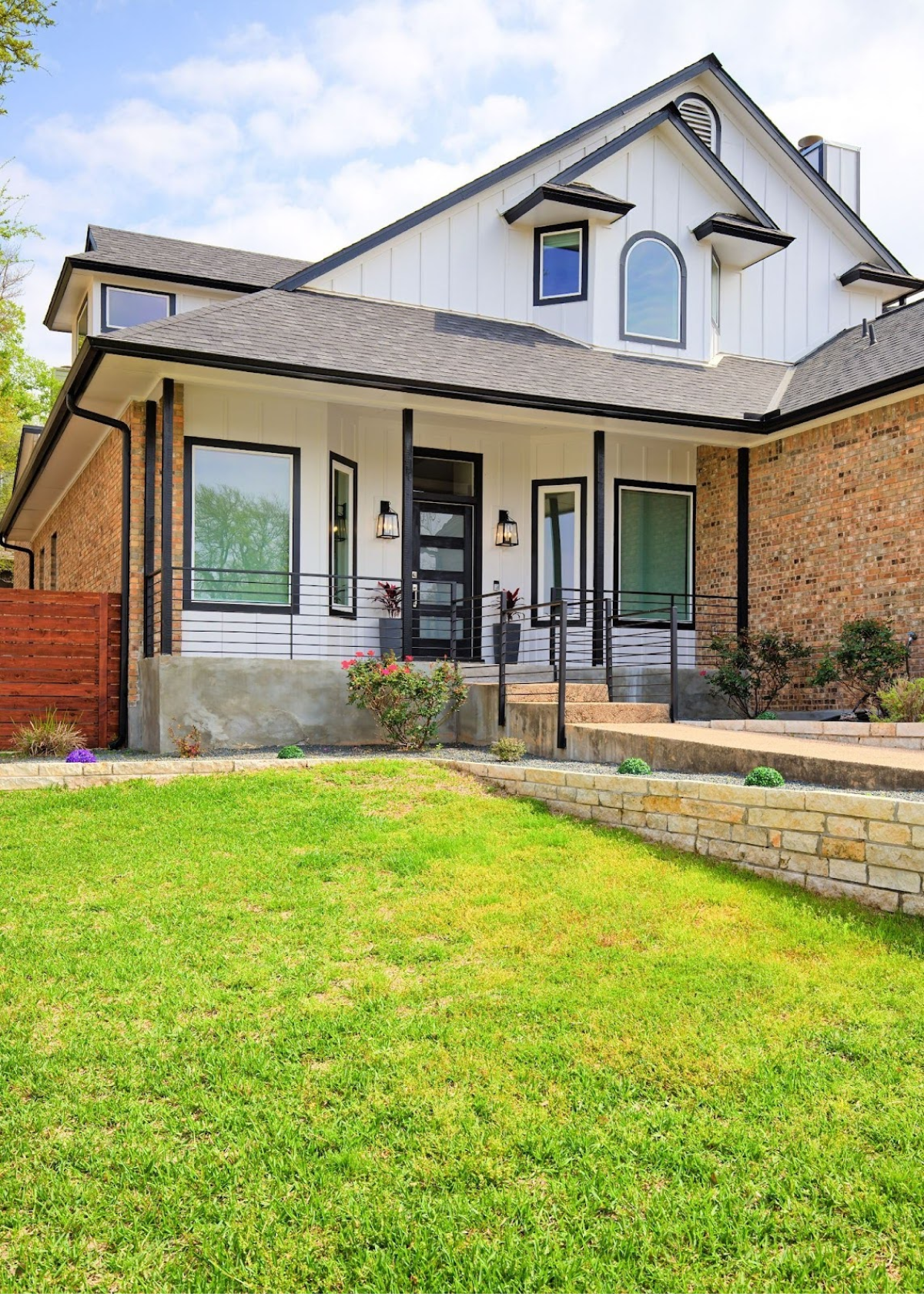 Modern white farmhouse with black trim and a spacious front yard.