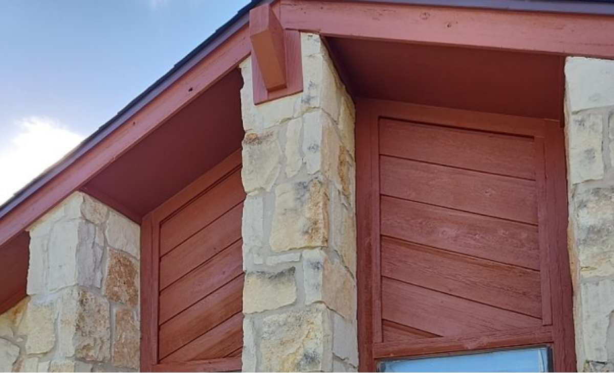 Red painted siding on a house with stone accents.