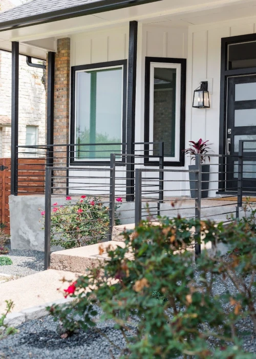 Close-up of a porch with black railings and vibrant flowers.