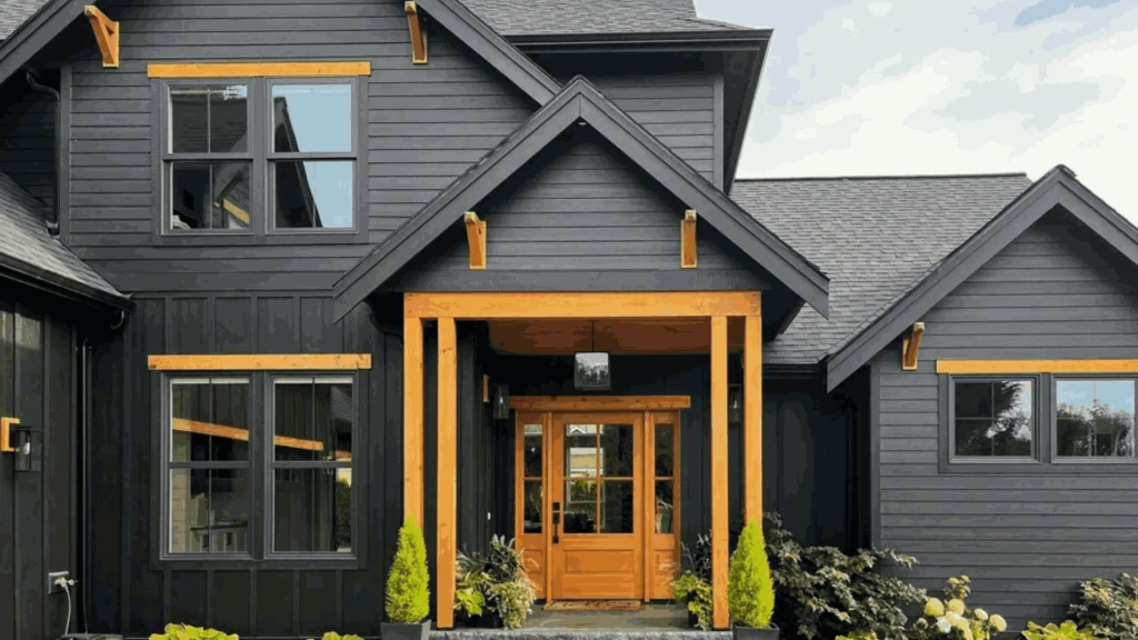 A modern black home with wooden accent trim and a large wooden front door.