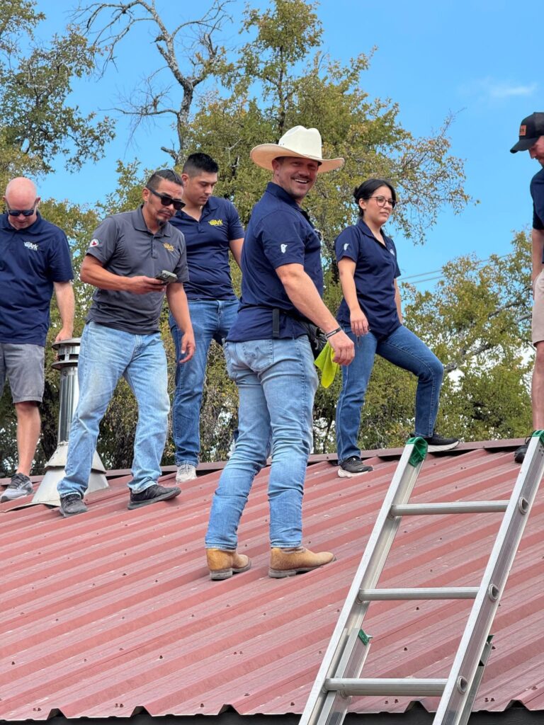 Ark Roofer founder Luke Secora with his team on a metal roof in Central Texas